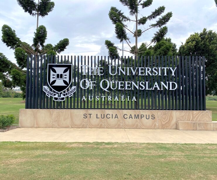 Entrance sign for the University of Queensland’s St Lucia campus, displaying the university crest and name against a landscaped background.